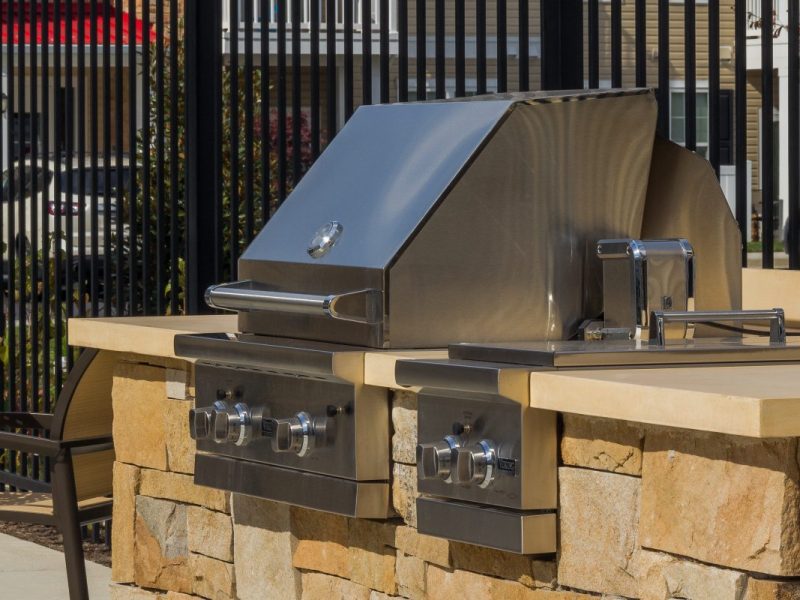 This image shows an outdoor barbeque area with a grill and picnic space.